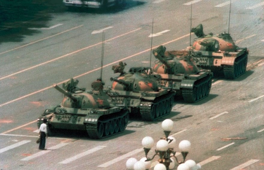 Tank Man, Jeff Widener, 1989.
The unidentified man in the photo is known only as "tank man." He was in the middle of shopping—take a look at the bags in his hands—but decided to try and stop these tanks from moving forward in Tiananmen Square. The drivers tried to make their way around him but he continued to block them. No fires were made, and the man was eventually removed from the scene.

The incident followed a crackdown which resulted in the deaths of hundreds of protestors. Photographer Jeff Widener notes that this photo shows that "[Tank man has] just had enough" ... "his statement is more important than his own life.