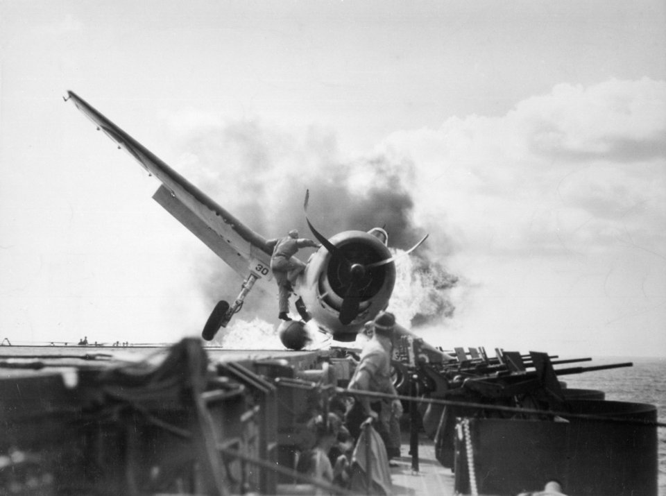 The catapult officer risks his life saving the pilot from a crashed and burning Hellcat on the USS Enterprise, 1943