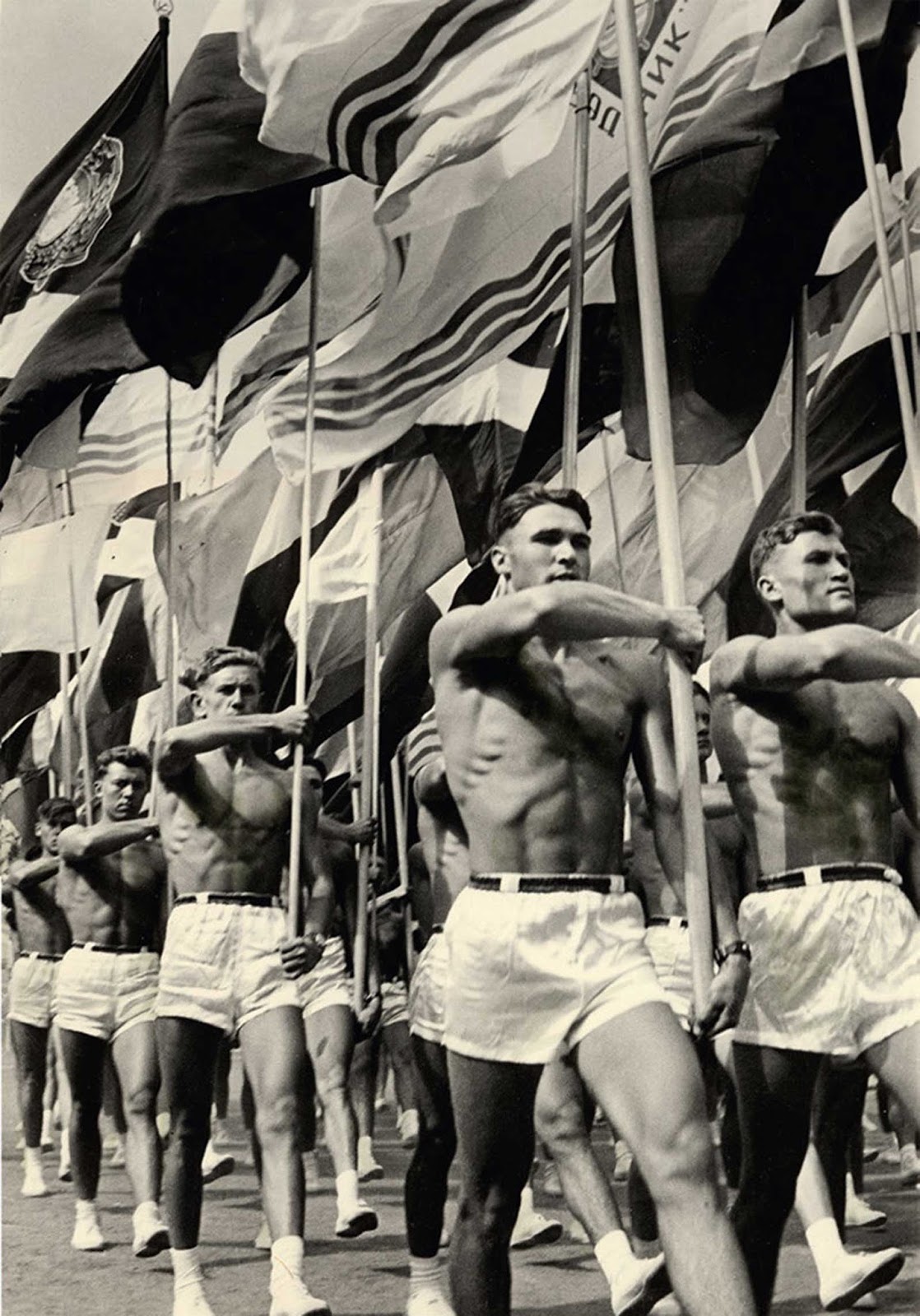 Soviet gym teachers parade in Moscow, 1956.

The Russian word used in the original title, “физкультурники“, is now usually translated as “gym teachers”, but at the moment of the parades meant “sportsmen/bodybuilders or athletes”. This is a legacy of Stalin era propaganda parades to promote physical fitness, mainly to make the people ready for heavy labor, possible wars and improve health of the nation.