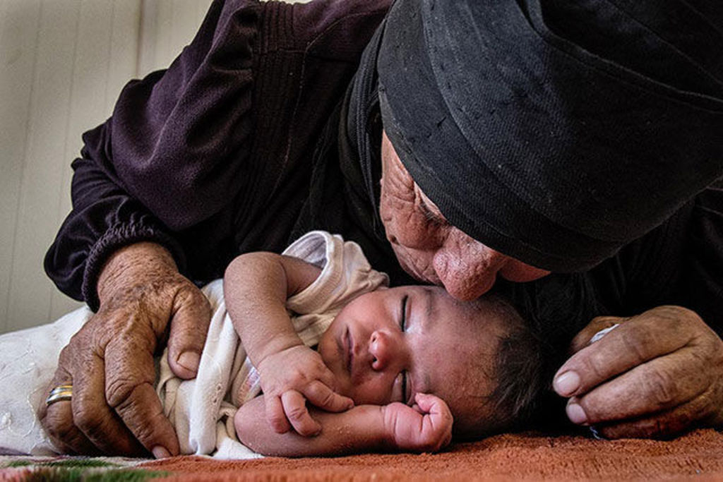 A Syrian refugee kisses the 10-day-old baby she carried with her to safety across the border into Jordan