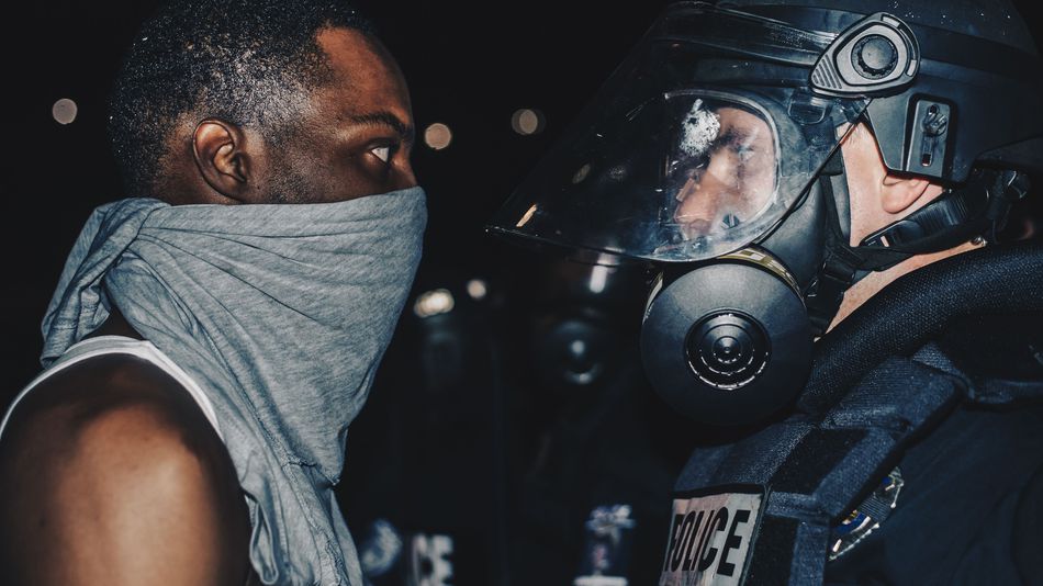 A protester faces off against a Charlotte police officer by Jonathan Brashear