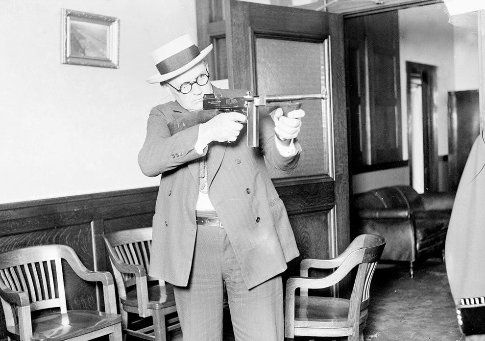Lieutenant William Shoemacher stands and aims a Thompson machine gun, or tommy gun, Chicago, 1926. The gun, developed for World War I, was very popular with gangsters due to its high rate of fire. From the Chicago Daily News collection