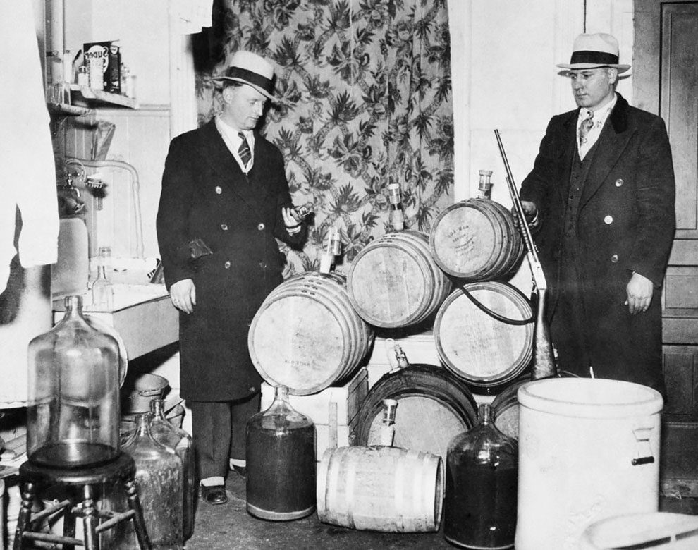 Police officers look over distilling equipment and guns confiscated during a Prohibition raid, Chicago, ca.1920s