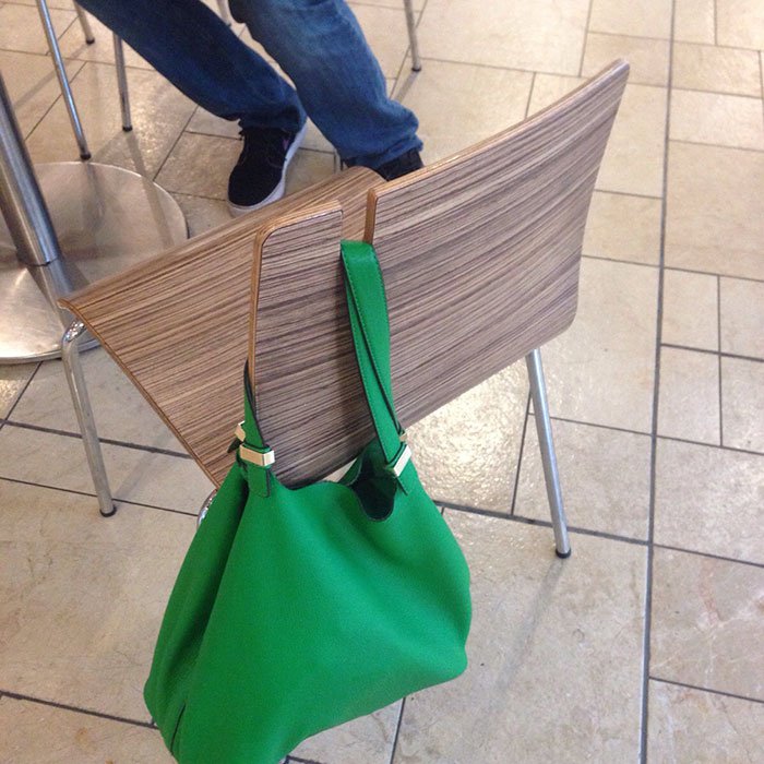 A restaurant uses chairs that have purse/bag holders.
