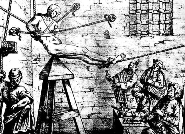 JUDAS CRADLE.

The victim would presumably be placed in the waist harness above the pyramid-shaped seat, with the point inserted into their an*s or v*gin*, then very slowly lowered by ropes. The subject is tortured by intense pressure and stretching of the orifice, eventually succumbing to tears in muscle tissue that could turn septic and kill from infection, or simply being impaled.