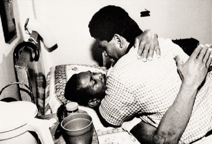 Roberto Duran hugs and kisses a dying Esteban de Jesus in his hospital bed as he dies from complications from AIDS, at a time where people feared catching the virus through contact