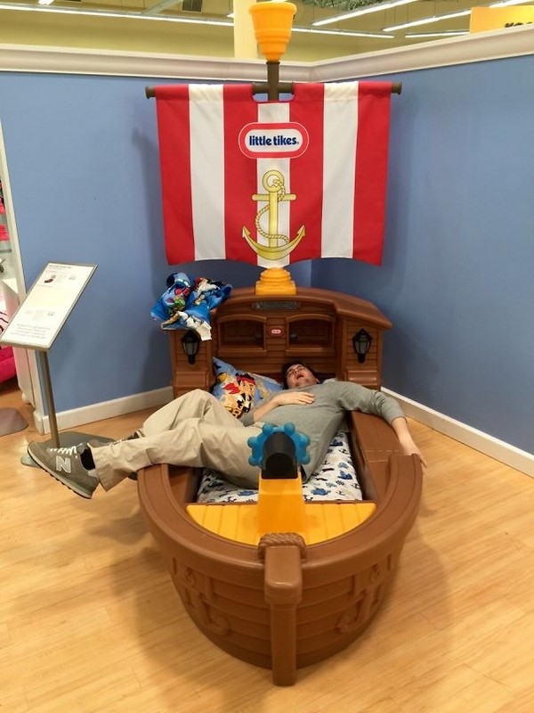 Man passed out in a Little Tikes Pirate ship bed.