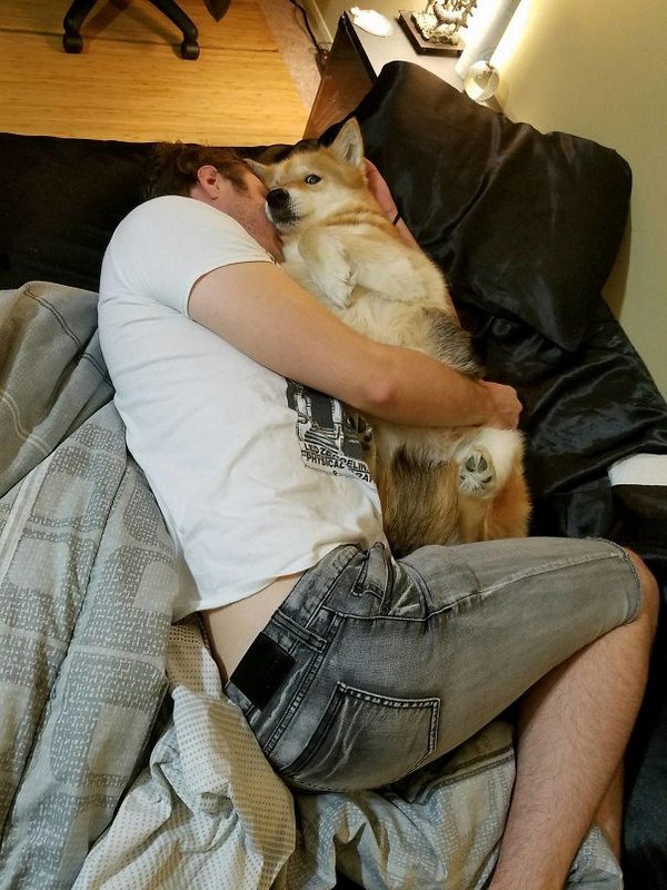 Man cuddling the dog giving the eye to the camera.