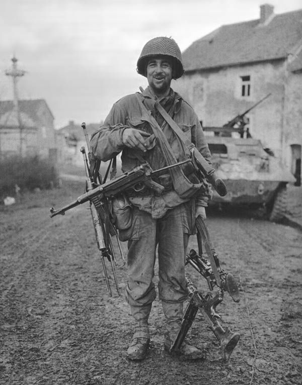 American soldier poses with captured German weaponry, 1944-45.

Every weapon has a signature, and using an enemy weapon can invite friendly fire. Prior to D-Day, American paratroops conducted mechanical training on German weapons (there was insufficient ammo for live fire training). With many men separated from their leg bags and weapons thanks to high-speed drops (which led to violent parachute openings), picking up a German weapon was fairly common. In the well-documented E company of the 2/506th PIR, Lt. Dick Winters briefly carried a German Mauser until he could recover an M1 from an American casualty (this is described in Steven Ambrose’s book and depicted in the TV miniseries). That had no consequences for him, but Sergeant Bill Guarnere had problems when he picked up an MG42. In his own words:
I went looking for a gun, and found a Thompson submachine gun. I also took a German MG-42 off a dead Kraut and started shooting it, but the gun made a noise that was distinctly German. The German guns went brrrrrrrrrrt! The American guns went bap-bap-bap-bap-bap. Every time I started shooting it, the Americans started shooting at me! I got shot at by a dozen or so of our own men. I threw it the hell away. You learn fast or you get killed. I grabbed an M1 instead.
