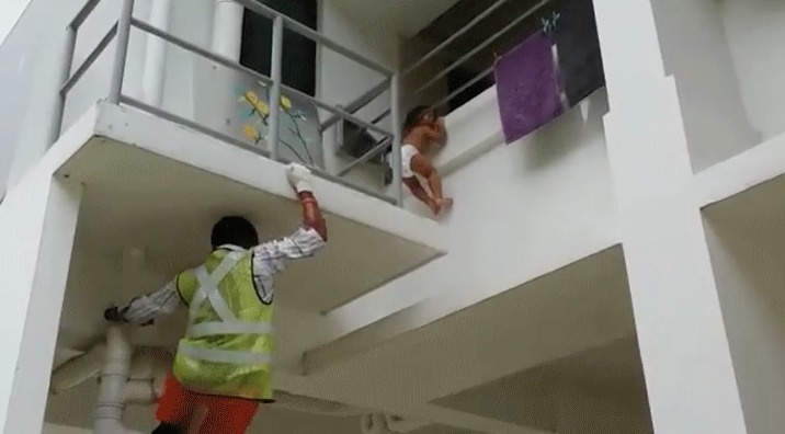 A baby was helplessly hanging for her life from a dangerously tall height.
Luckily, a foreign worker heard and spotted her just in the nick of time to climb up the building and save her.