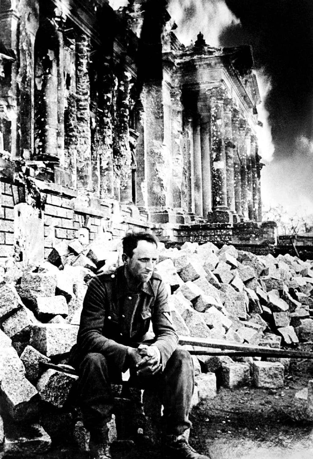 German soldier during the Battle of Berlin as the Reichstag burns behind him, April 1945