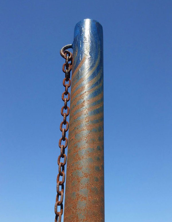 Cool pattern on a pole with a chain that has been formed from years of repetitive use.