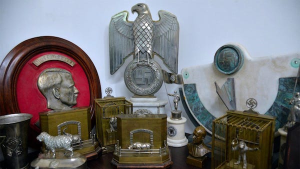 Just outside Buenos Aires, in a hidden room in a suburban home, a secret collection of 75 Nazi artifacts has been uncovered by police. The memorabilia was believed to be owned by high-ranking Nazi officials during WWII, further proving their existence in South America following that war. 

The trove includes a bust relief portrait of Adolf Hitler, a statue of an eagle above a swastika, a knife, a box of children's harmonicas and puzzles, an hourglass, a medical device that is used to measure the size of a person's head, and a World War II German army mortar aiming device. There is also a photo negative of Hitler holding a magnifying glass which is also in the collection. 

All of the Nazi memorabilia is believed to be original. Argentine Security Minister Patricia Bullrich said she'll ask to have the items donated to the Holocaust Museum of Buenos Aires.