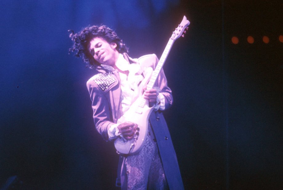 The guitar, Purple Rain (1984)
Dave Rusan, guitar maker (in an interview with Premiere Guitar, 2016): “Prince wasn’t much for small talk. He could certainly express himself if he felt it was necessary, but in this case he didn’t all that much. So he had this bass with him in the store that day — I’d actually worked on it before — and his main requirements were just that the guitar should be in that shape, and it had to be white, and it had to have gold hardware. I think he specified he wanted EMG pickups, but compared to all the conversations you would have with somebody about a custom guitar, there wasn’t anything else he wanted to talk about — the size of the neck, the frets, the playability features, or anything. He did come in once after that, and Jeff [Hill, the owner of Knut-Koupée Music] was able to get him to make a few comments, but I figured if he’s not going to tell me what he wants, I’ll make something I think he’ll like and hope for the best.”