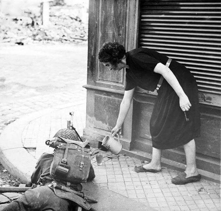French woman pours a hot cup of tea for a British soldier fighting in Normandy, 1944