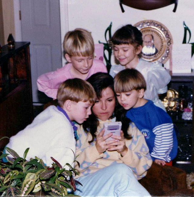 Throwback to the 90's of girl playing Gameboy and kids huddled around to get a peek.