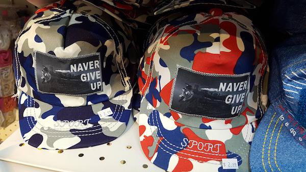 Hats for sale that say NAVER give up.