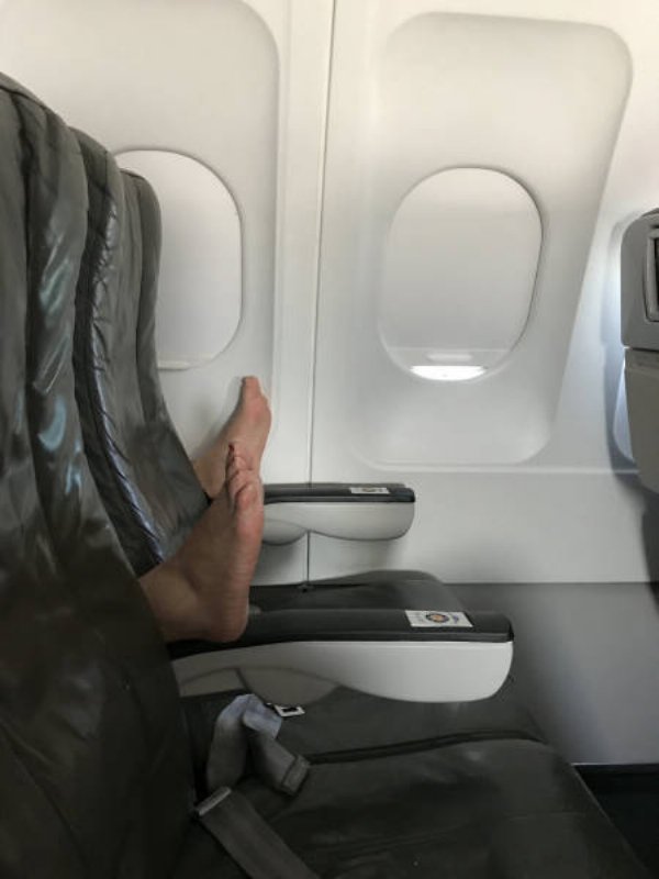 Airplane ride with feet coming from the seat behind you.