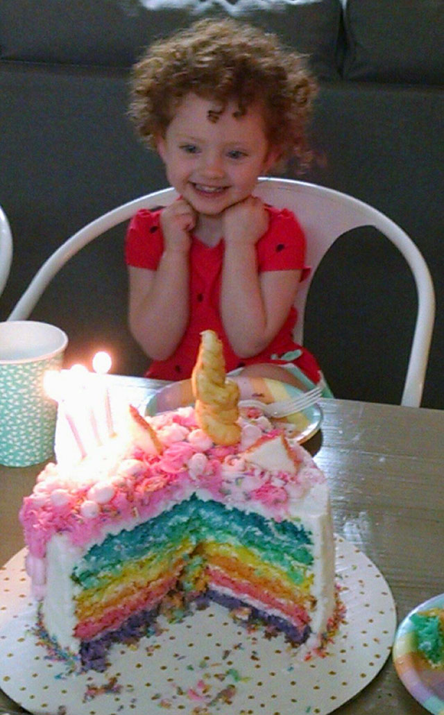 Girl excited to eat her rainbow cake on her birthday