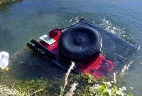 Jeep that has fallen in the water and about to go fully submerged.