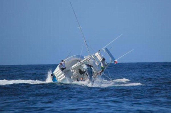 Man catching a big fish in a boat that is capsizing out at sea.