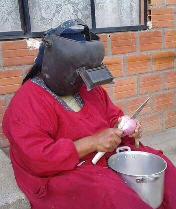 Russian woman peeling onions with a huge knife and a welding mask to protect her eyes.