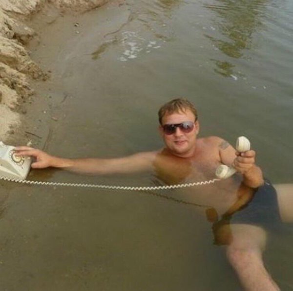 Russian man with a rotary phone in a muddy swimming hole.
