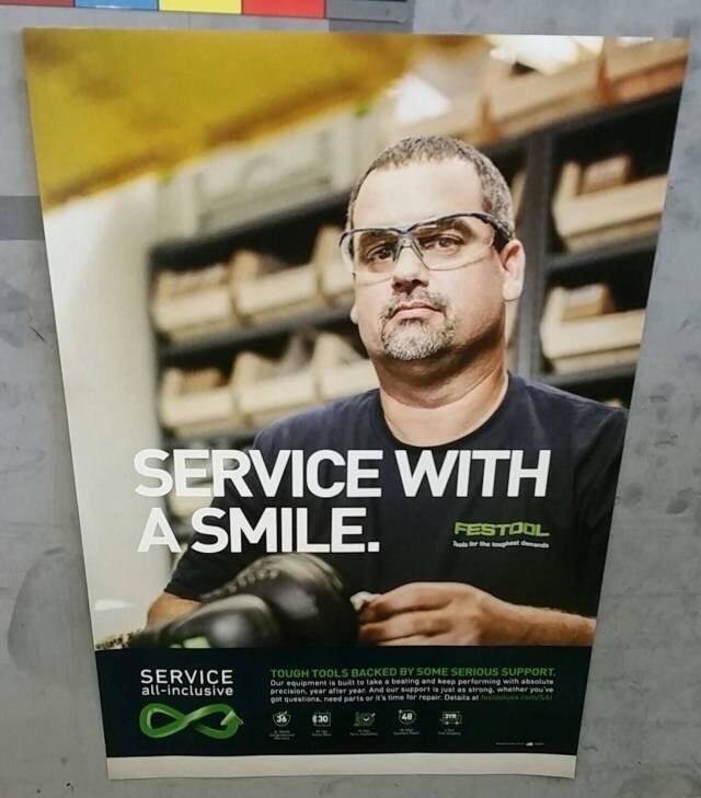 Sign that says Service with A Smile but the man in the advertisement is not smiling, not at all.