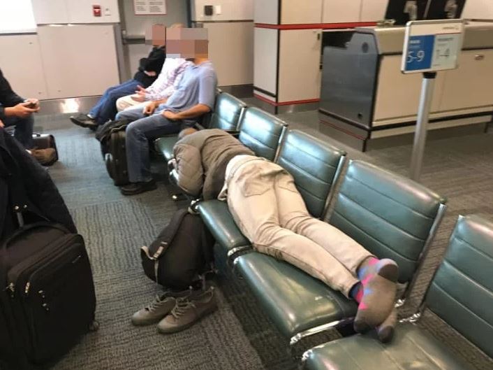 Man sleeping on airport bench taking up all the spots