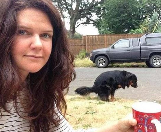 Woman taking an inappropriate selfie with her dog pooping in the background