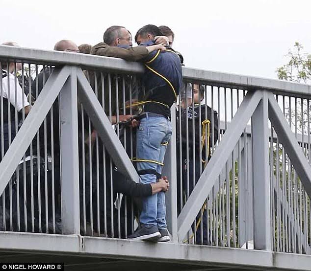 People holding on to a man trying to commit suicide