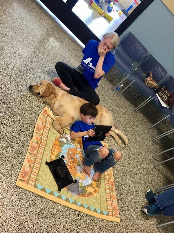 A mother watches her severely autistic son, whom she cannot hug, bond with his service dog