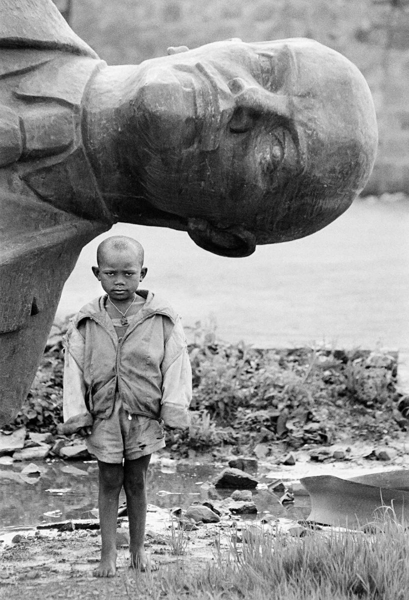 Boy standing in front of fallen statue of Lenin, Ethiopia, 1991