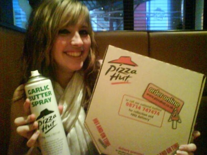 Pizza Hut have a can of spray on garlic that they spray on their all their pizzas. At least they did in 2012.