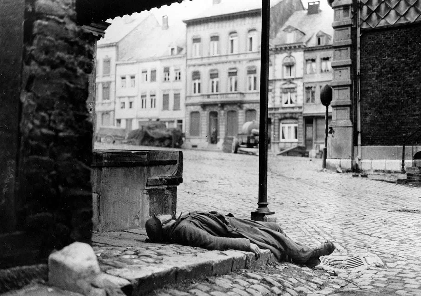 A dead German soldier, killed during the German counter offensive in the Belgium-Luxembourg salient, is left behind on a street corner in Stavelot, Belgium, on January 2, 1945, as fighting moves on during the Battle of the Bulge.