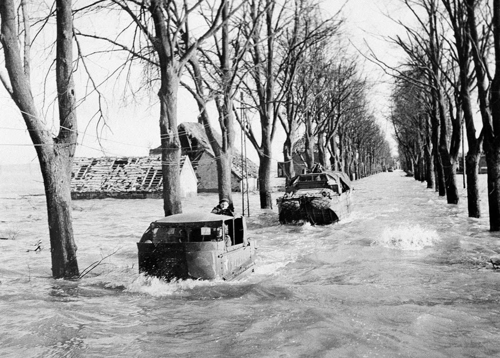 A party sets out to repair telephone lines on the main road in Kranenburg on February 22, 1945, amid four-foot deep floods caused by the bursting of Dikes by the retreating Germans. During the floods, British troops further into Germany have had their supplies brought by amphibious vehicles.