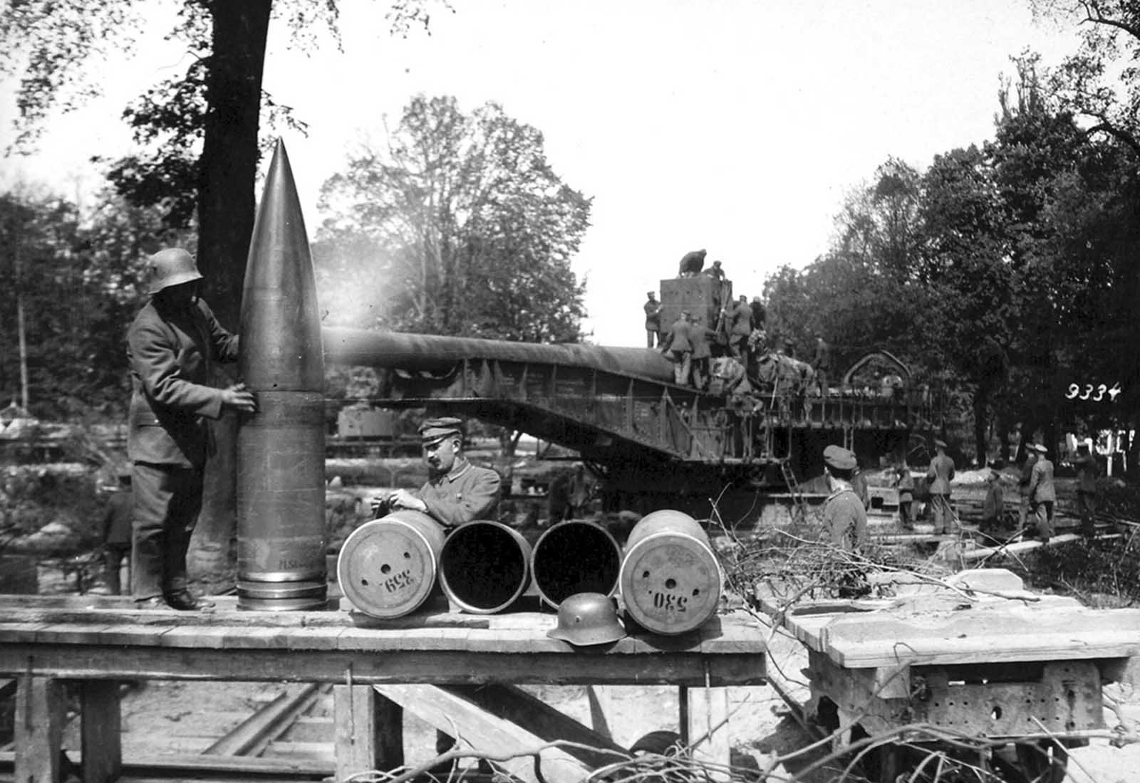 A German soldier rubs down massive shells for the 38 cm SK L/45, or “Langer Max” rapid firing railroad gun, ca. 1918. The Langer Max was originally designed as a battleship weapon, later mounted to armored rail cars, one of many types of railroad artillery used by both sides during the war. The Langer Max could fire a 750 kg (1,650 lb) high explosive projectile up to 34,200 m (37,400 yd).