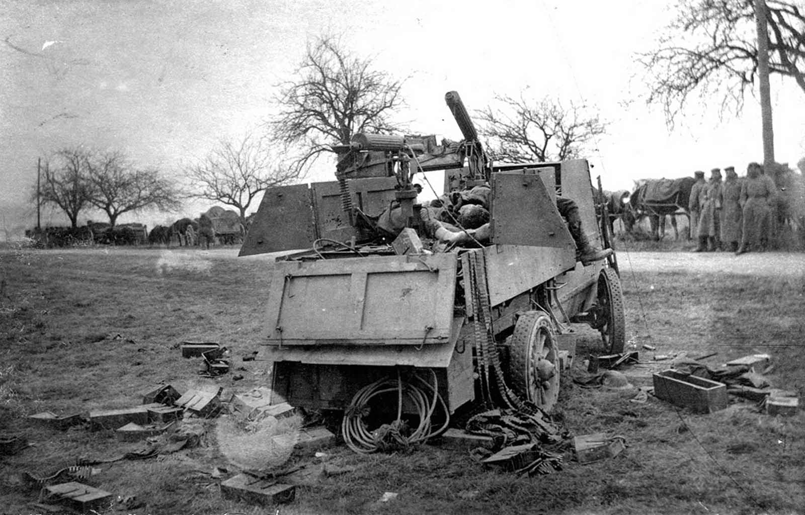 A German column looks over a destroyed Canadian Armored Autocar, the bodies of Canadian soldiers, empty belts, and cartridge boxes strewn about.