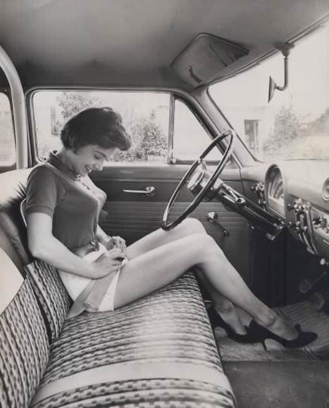 Girl with early car seat belt, ca. 1950s.