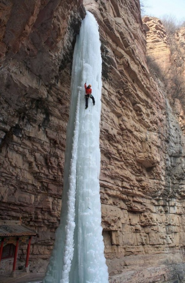 A man climbing this frozen waterfall.