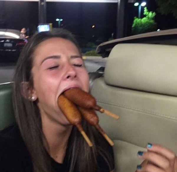 girl with corn dogs in mouth