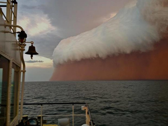 A towering red dust storm roaring over the ocean near the western Australian coast