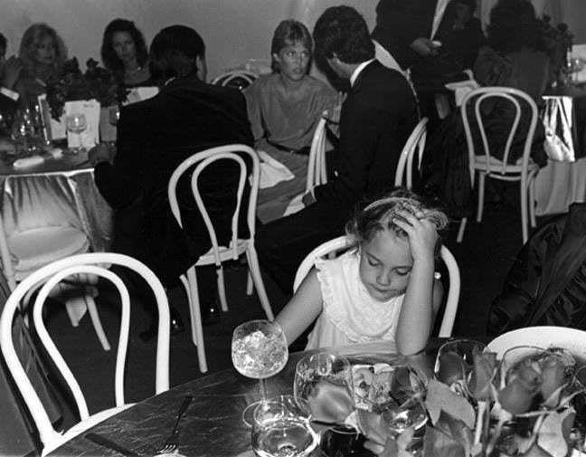 A very young Drew Barrymore alone at a party with the weight of the world on her small shoulders, 1983.
