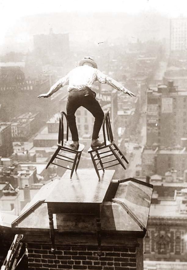 A man does a balancing act on top of a skyscraper in NYC, US in 1926.
