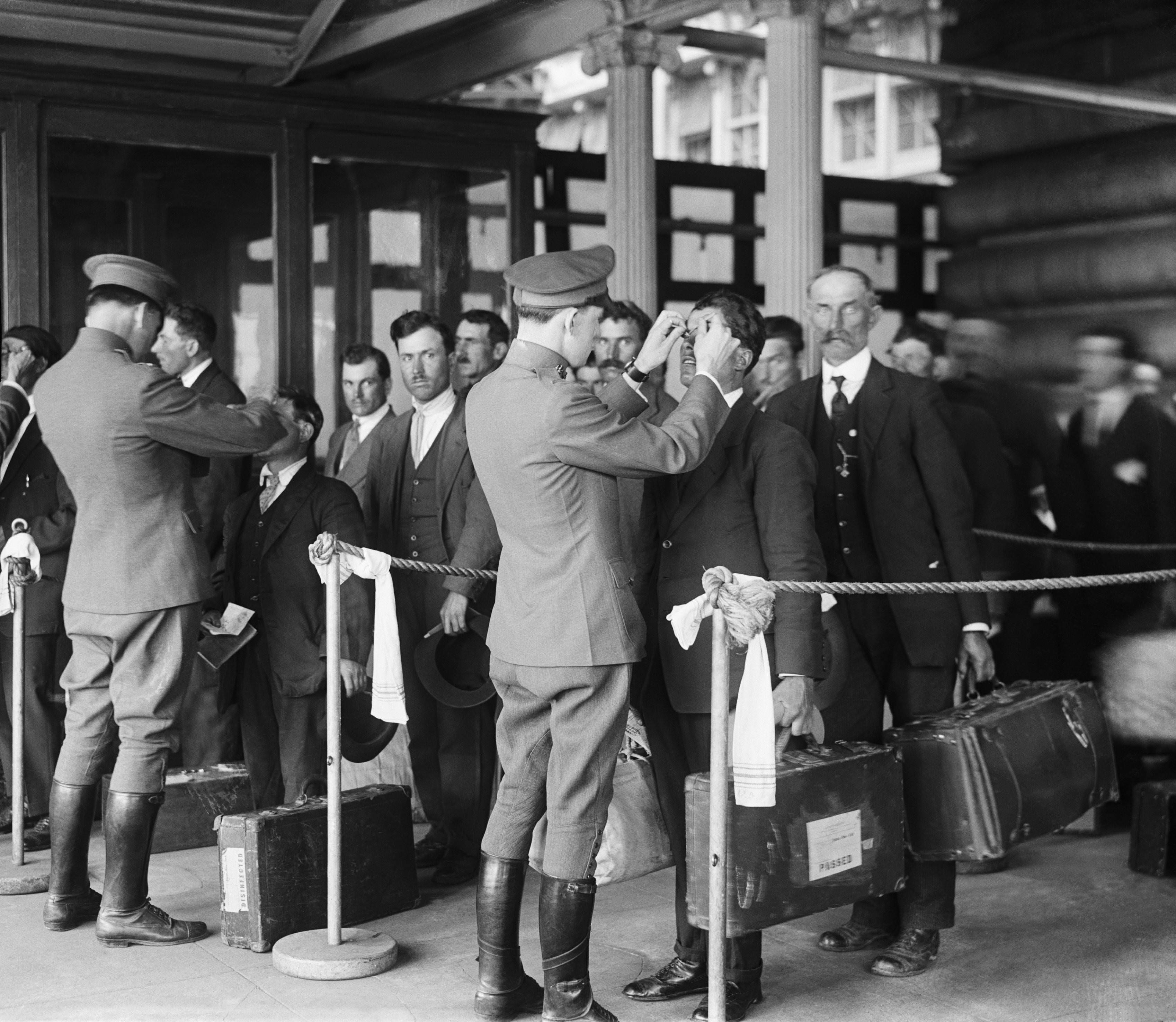 Officials looking for disease or lice on arriving immigrants at Ellis Island off New York City, US in 1923.