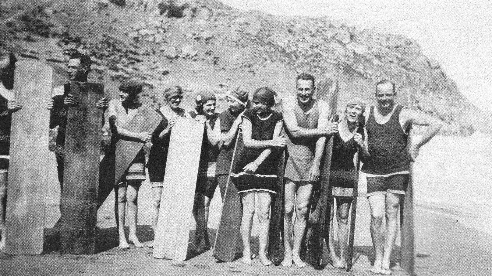 Roy Burston with family and friends all using early versions of a boogie board or bellyboard at the beach in Australia in 1924.