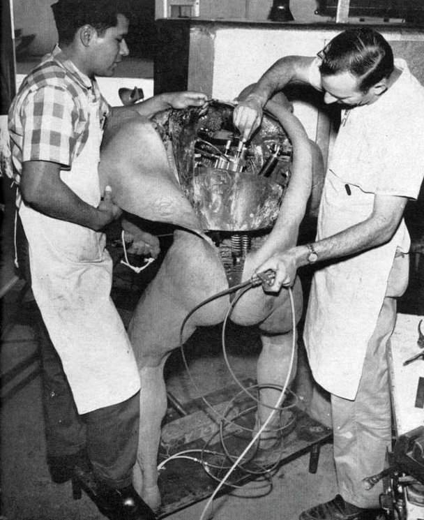 2 Special effects crew members work on a caveman prop for the Worlds Fair in 1964.