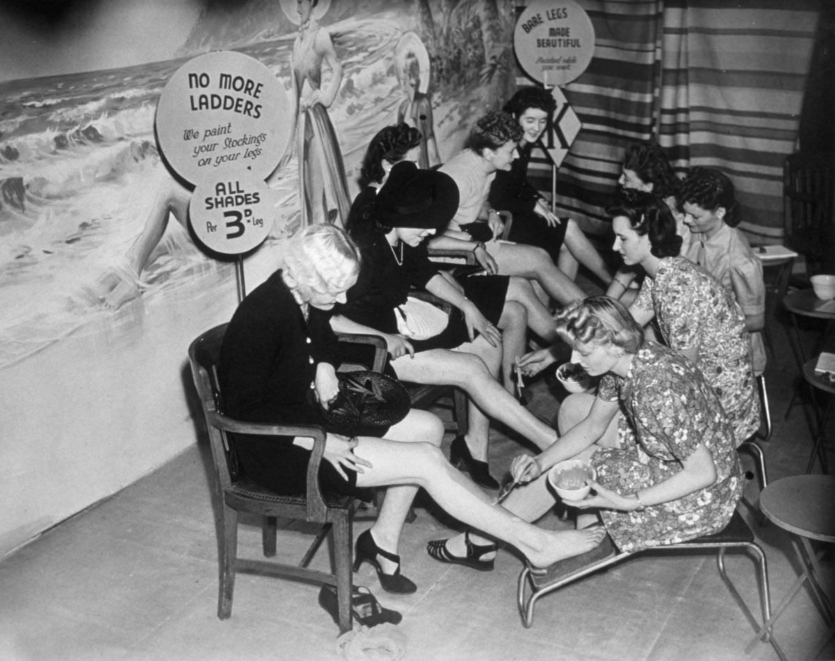 Women having their stockings painted on in London, England in 1941.