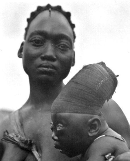 A mother from the tribe Mangbetu holds her son whom has an elongated skull due to head binding in the Congo in 1950.