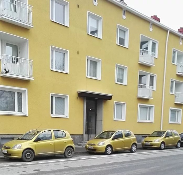 3 cars of the same color are parked in front of a matching building.